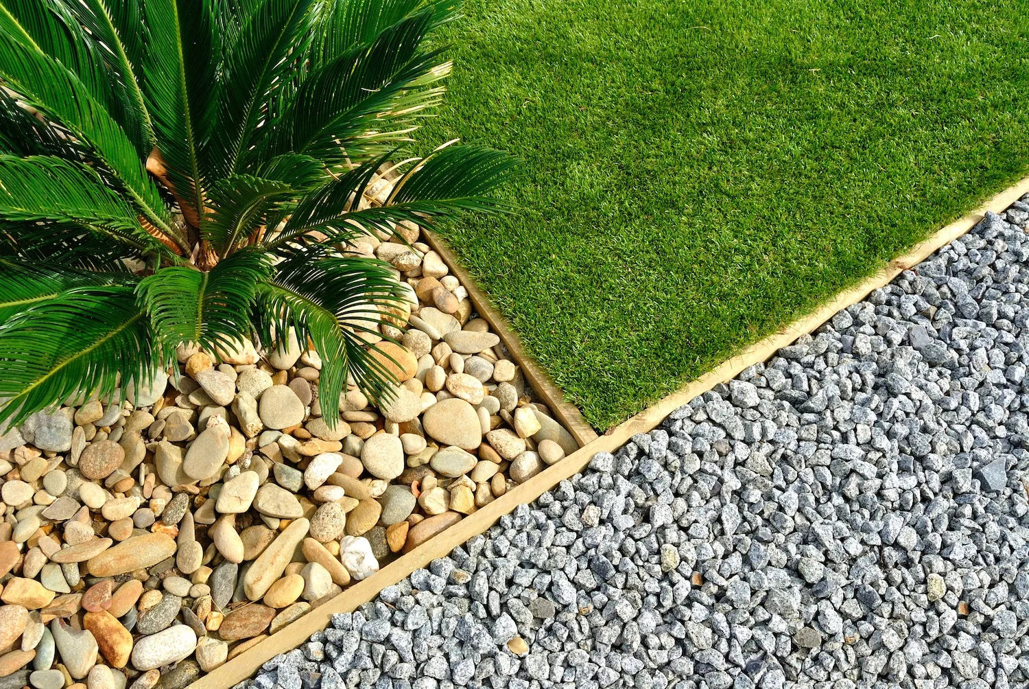 Landscaped garden bed edging with river pebbles and lawn