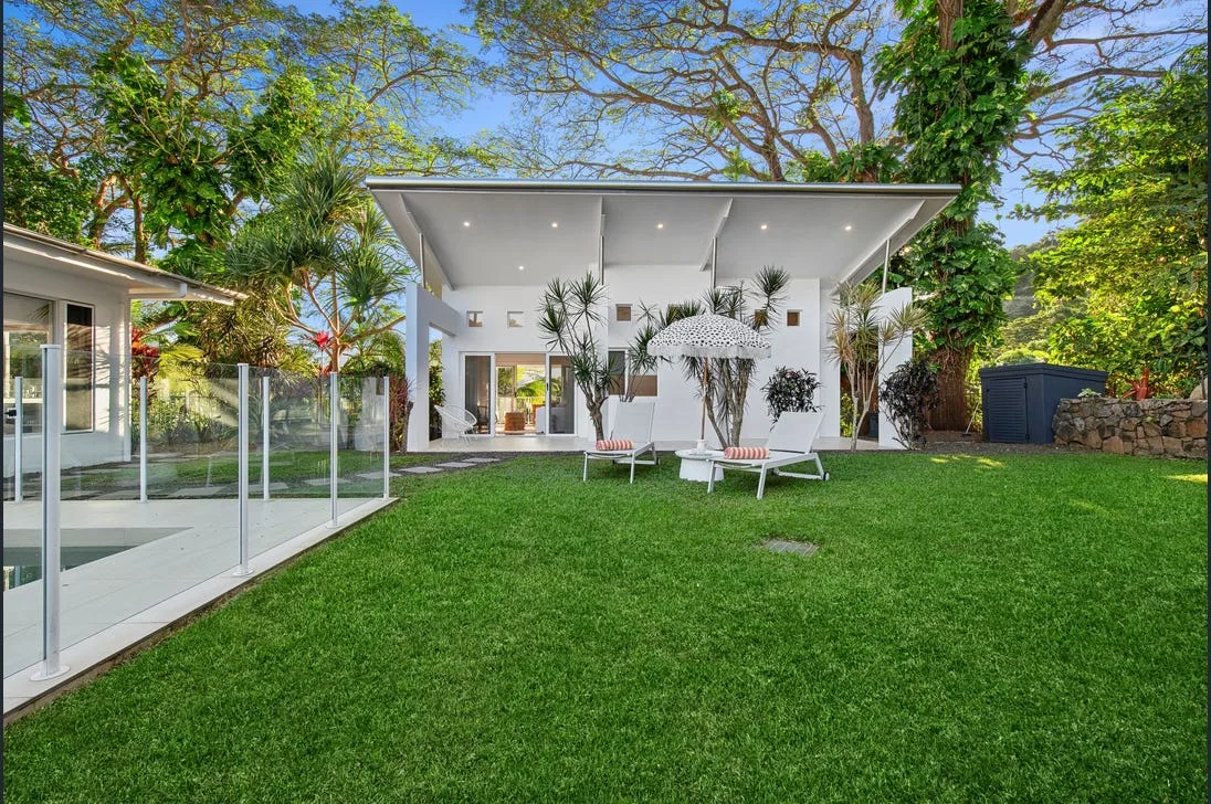 Pool with glass fencing, lawn and sun loungers