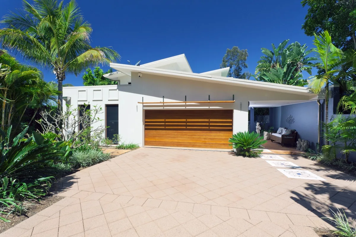 Modern Brighton home with palm trees and landscaped garden beds along the driveway