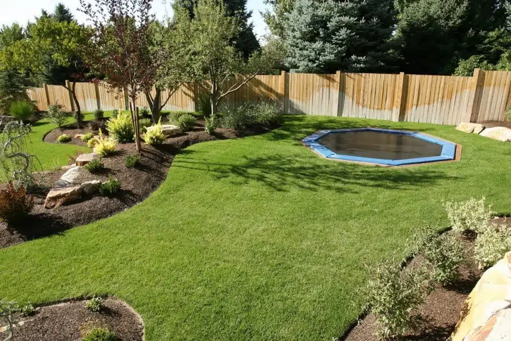 Landscaped backyard lawn with garden edging and a covered in-ground pool
